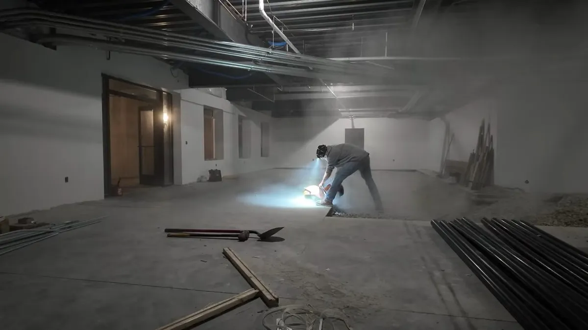 worker marks the floor in a large unfinished commercial build-out for Maricopa Plumbing Pros