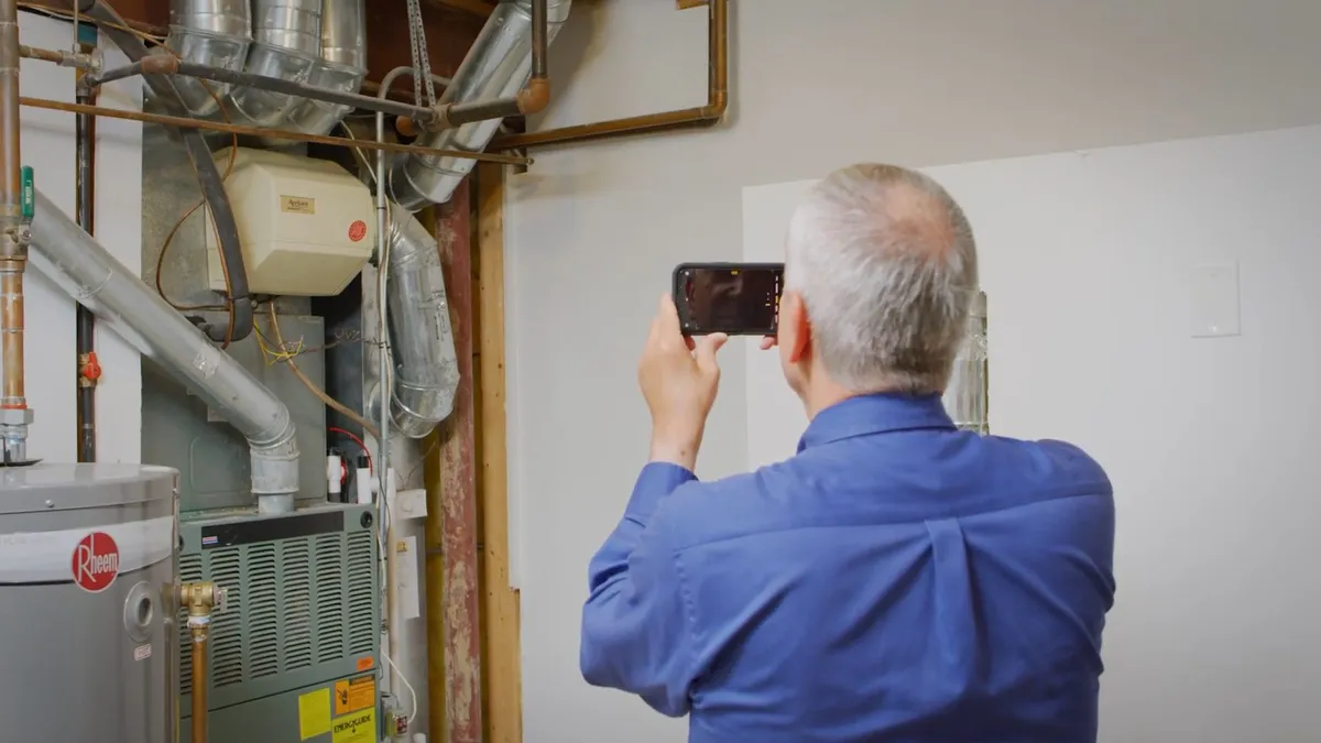 technician photographs water-treatment and heater equipment in a utility room for Maricopa Plumbing Pros